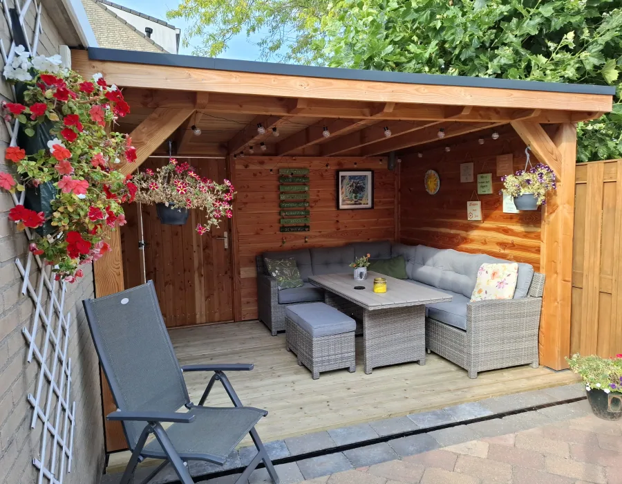 Veranda met loungeset en bloeiende hangplanten - Tuinaanleg Zoetermeer